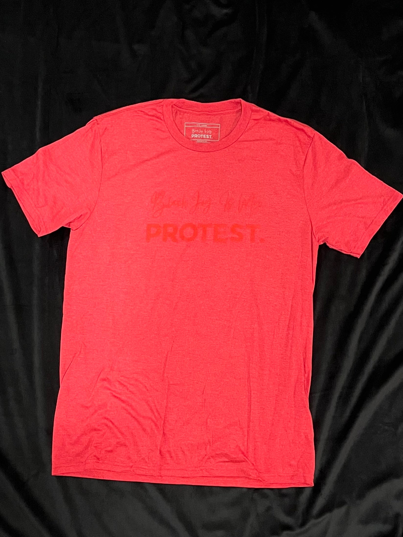 Red t-shirt with darker red text that reads Black Joy Is My Protest on a black background