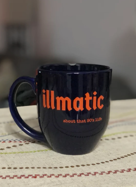 Blue mug with 'illmatic' in orange text on a patterned surface